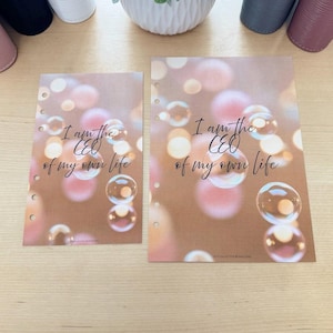 May include: Two planner inserts with the text "I am the CEO of my own life" in a handwritten style font. The inserts have a brown background with a bokeh effect and bubble illustrations. The inserts are pre-punched.