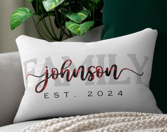 May include: White cushion with the text "FAMILY johnson EST. 2024" in grey and red plaid lettering.