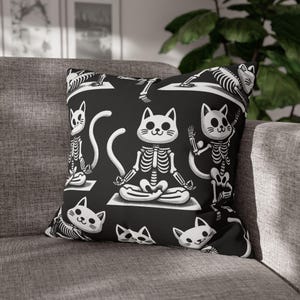 May include: Black and white throw pillow with a repeating pattern of skeleton cats in yoga poses. The cats are in a seated meditation pose with their eyes closed.