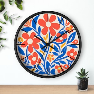 May include: A round wall clock with a black frame and a white face. The clock face features a colorful floral design with red, orange, yellow, and blue flowers and leaves.