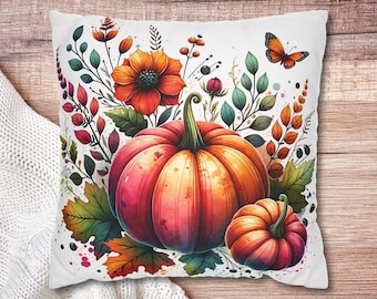 May include: White square pillow with a watercolor design featuring a large orange and red pumpkin, a smaller pumpkin, and fall foliage. A butterfly and orange flowers are also included in the design.