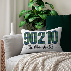 Puede incluir: Almohada blanca con un patrón de cuadros verdes y azules. Los números 90210 están impresos en azul en la almohada con el texto "The Marshalls" en cursiva negra.