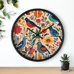 May include: A black clock with a white face and black hands. The clock face features a colourful floral design with birds and a sunflower. The birds are blue, red, and green.