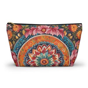 May include: A colorful zippered pouch with a mandala design featuring a central flower surrounded by concentric circles of red, orange, blue, and green. The background is a dark blue with pink flowers.