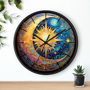 May include: A round wall clock with a black frame. The clock face features a celestial design with a sun, moon, and stars in shades of gold, blue, and purple. The clock hands are black.