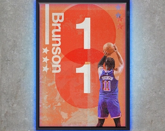 Pode incluir: Obra de arte emoldurada com um jogador de basquete em uma camisa roxa com o número 11 e o nome Brunson. O fundo tem um círculo laranja com o número 11 em branco. A moldura tem uma luz de néon azul.