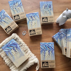 May include: Several bars of soap with a blue and white swirl design and a wolf imprint. The soap bars are packaged in boxes with the text "ALPAKAS Regen" and "Sommer". A small white alpaca figurine and a washcloth are also present.