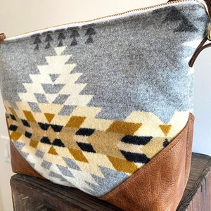 Puede incluir: Un bolso tote de patr&oacute;n geom&eacute;trico gris y marr&oacute;n con fondo de cuero y cierre de cremallera.