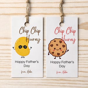May include: Two rectangular white gift tags with twine loops. The left tag features a yellow chip character with sunglasses and the text Chip Chip Hooray Happy Father's Day from Helen. The right tag shows a chocolate chip cookie with the same text.