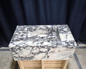 Peut inclure: Un lavabo en marbre blanc avec des veines violettes et brunes, posé sur un socle en bois à lattes.