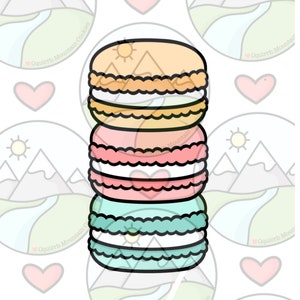 May include: A stack of three pastel-colored macarons. The macarons are decorated with a simple white swirl design and a small sun on the top macaron.