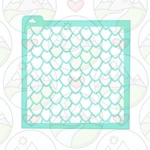 May include: A teal blue stencil with a pattern of overlapping scales. The stencil is rectangular and has a mountain peak design at the top.