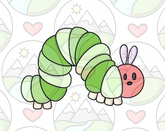 May include: A green and pink cartoon caterpillar with a curled body and a pink head with two purple antennae. The caterpillar is on a white background with a repeating pattern of mountains, hearts, and suns.