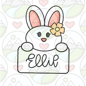以下が含まれることがあります： ピンクの耳と頭に黄色い花をつけた白いウサギが、「Ellil」と書かれた看板から顔を出しています。背景は、白地に山とハートの模様です。