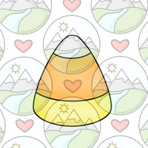 May include: A yellow and orange candy corn cookie with a mountain scene and a sun on the bottom. The cookie is decorated with a heart in the centre.