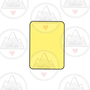 May include: A yellow cookie cutter in the shape of a rectangle with rounded corners. The cookie cutter has a small heart shape cut out in the center.