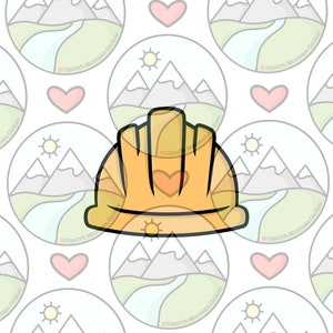 May include: A yellow construction worker helmet cookie cutter with a heart on the front. The cookie cutter is on a white background with a repeating pattern of mountains, a river, a sun, and a heart.