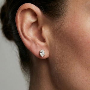Puede incluir: Pendientes de diamantes con forma ovalada. Los pendientes están engarzados en un metal de color claro. Los diamantes tienen un corte brillante y brillan. Los pendientes son una joya clásica.