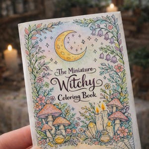 May include: A miniature colouring book titled "The Miniature Witchy Coloring Book" with a crescent moon, stars, mushrooms, flowers, and candles. The cover is decorated with a colourful, whimsical illustration with a fantasy theme.
