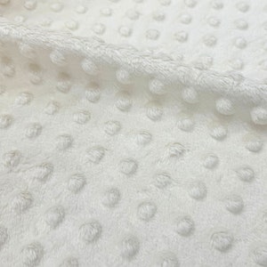 May include: White plush fabric with a textured dot pattern. The fabric is soft and has a subtle sheen.
