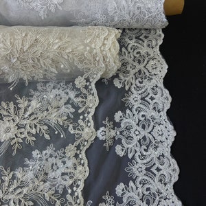 May include: White floral lace fabric with a delicate pattern. The lace is rolled up and the fabric is sheer and lightweight.