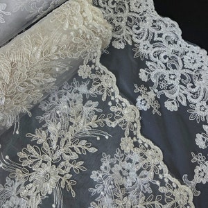 May include: White floral lace trim with a scalloped edge. The lace is delicate and intricate, with a floral pattern.