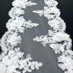 May include: White lace trim with 3D floral embellishments and pearl accents. The lace is delicate and intricate, with a scalloped edge.