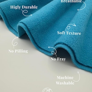 May include: A bright turquoise fleece fabric with white text labels pointing to features: Higly Durable, Breathable, Soft Texture, No Pilling, No Fray, and Machine Washable. A circular logo with the letters ST is visible at the bottom center.