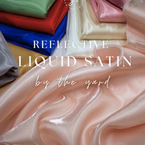 May include: A collection of reflective liquid satin fabric in various colors, including pink, blue, red, and green. The image features the text "REFLECTIVE LIQUID SATIN by the yard". The fabric has a shiny, flowing appearance.