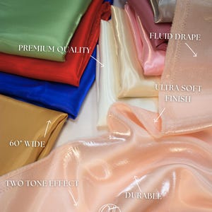 May include: A collection of colorful satin fabric samples in shades of green, red, blue, gold, white, pink, and peach. The fabric is labeled as premium quality, 60" wide, with a fluid drape, ultra-soft finish, two-tone effect, and durable.
