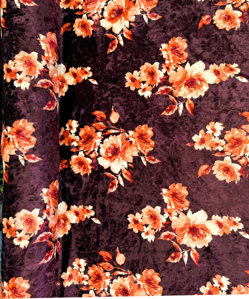 May include: Burgundy velvet fabric with a floral pattern featuring orange and cream flowers. The fabric has a textured, crushed velvet look.