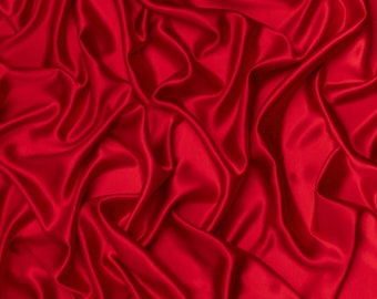 May include: A close-up of a smooth, red satin fabric with soft, flowing folds and wrinkles.