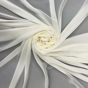 May include: A white sheer fabric, folded and arranged in a spiral shape. The fabric is soft and delicate, with a smooth texture.