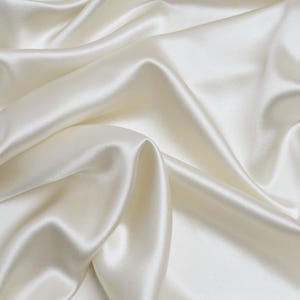 May include: A smooth, white satin fabric with soft, flowing folds. The fabric is luxurious and elegant, with a subtle sheen.