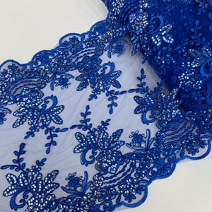 May include: Royal blue lace trim with a floral design and silver sequins. The lace is delicate and has a scalloped edge.