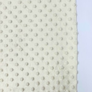 May include: Close-up of a white fabric with a textured pattern of small raised dots.