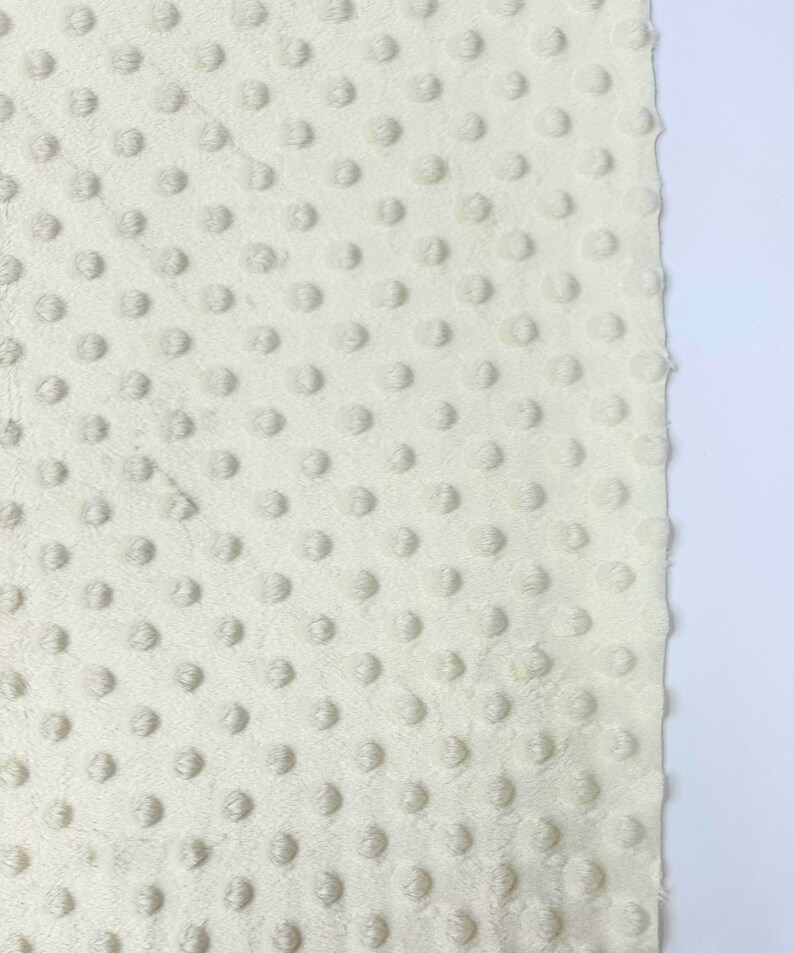 May include: Close-up of a white fabric with a textured pattern of small raised dots.