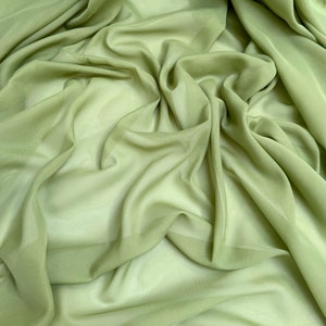 May include: A piece of soft, light green fabric with a smooth, silky texture. The fabric is draped and folded, creating a flowing, elegant look.