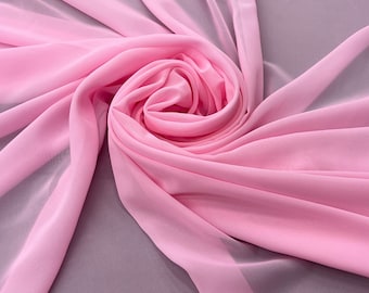 May include: A soft, pink fabric draped and folded in a swirling pattern. The fabric is sheer and translucent, creating a delicate and airy look.