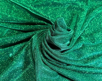 May include: Close-up of a vibrant green fabric with a shimmering, glittery texture. The material is draped and folded, creating a dynamic pattern of light and shadow. The fabric's surface reflects light, giving it a luxurious appearance.