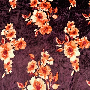 May include: Burgundy velvet fabric with a floral pattern in shades of orange and cream. The flowers are a mix of roses and smaller blooms.