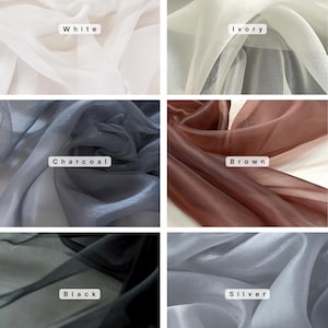 May include: A collection of sheer fabric swatches in various colors. The swatches include white, ivory, charcoal, brown, black, and silver. Each swatch has a label with its color name. The fabric appears lightweight and flowing.