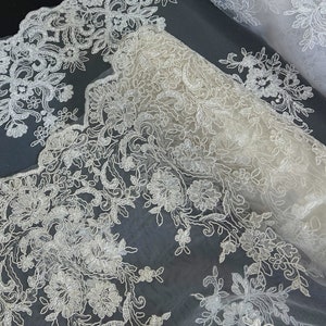 May include: White lace fabric with a delicate floral pattern. The lace is on a sheer mesh background.