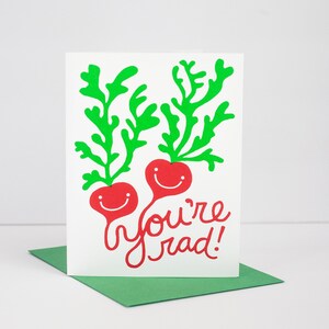 May include: A white card with two red radishes with green tops and smiling faces. The text "you're rad!" is written in red cursive.