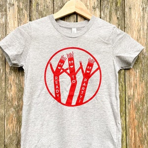 May include: Gray t-shirt with a red circle graphic of three inflatable tube men with the text "Ready to Party" around them.