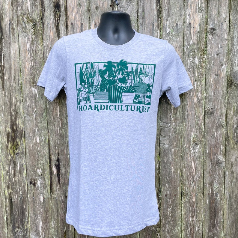 K&ouml;nnte beinhalten: Ein graues T-Shirt mit einer gr&uuml;nen Grafik von Topfpflanzen und dem Text "HOARDICULTURIST" auf der Vorderseite.
