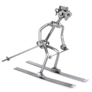 May include: A silver metal sculpture of a skier with a ski pole and skis. The skier is made of nuts, bolts, and other metal pieces.