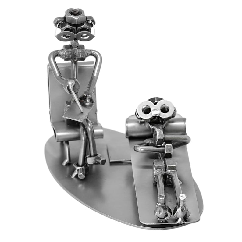 K&ouml;nnte beinhalten: Eine Metallskulptur, die einen Therapeuten zeigt, der auf einem Stuhl sitzt, und einen Patienten, der auf einer Couch liegt. Beide Figuren sind aus Muttern, Schrauben und anderen Metallteilen gefertigt.