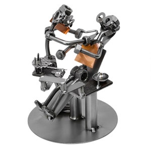 May include: A metal sculpture of a dentist working on a patient. The sculpture is made of nuts, bolts, and other metal pieces. The dentist is holding a drill and the patient is sitting in a chair.