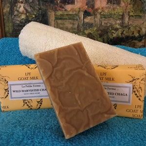 May include: Two bars of goat milk soap with a yellow and brown label. The label reads "LPF Goat Milk" and "La Petite Ferme... Wild Harvested Chaga Goat Milk Soap".